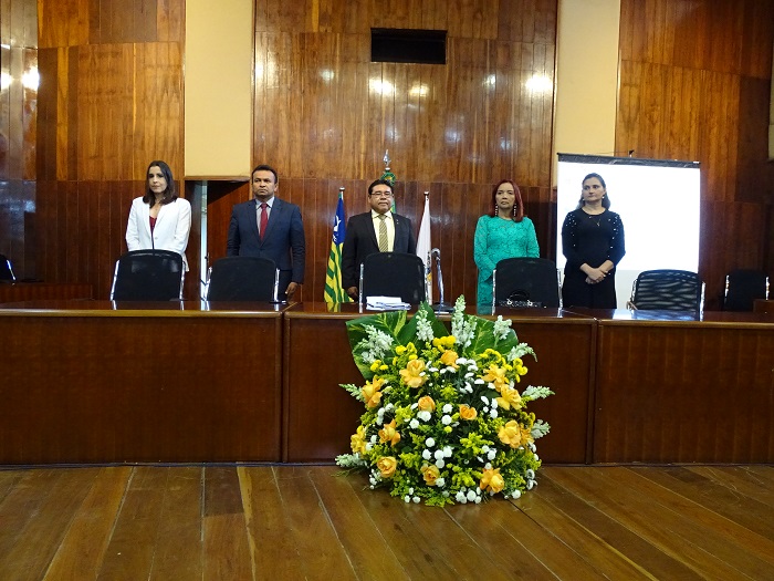 Pessoas de pé atrás de uma mesa com arranjo de flores