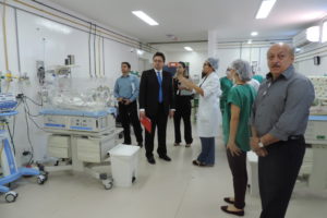 Pessoas de pé dentro de uma UTI, as pessoas conversam enquanto olham os equipamentos hospitalares