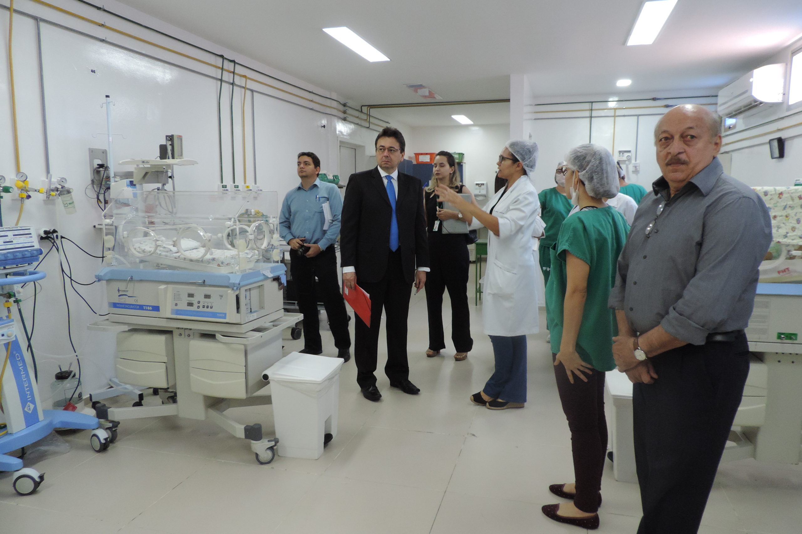 Pessoas de pé dentro de uma UTI, as pessoas conversam enquanto olham os equipamentos hospitalares 