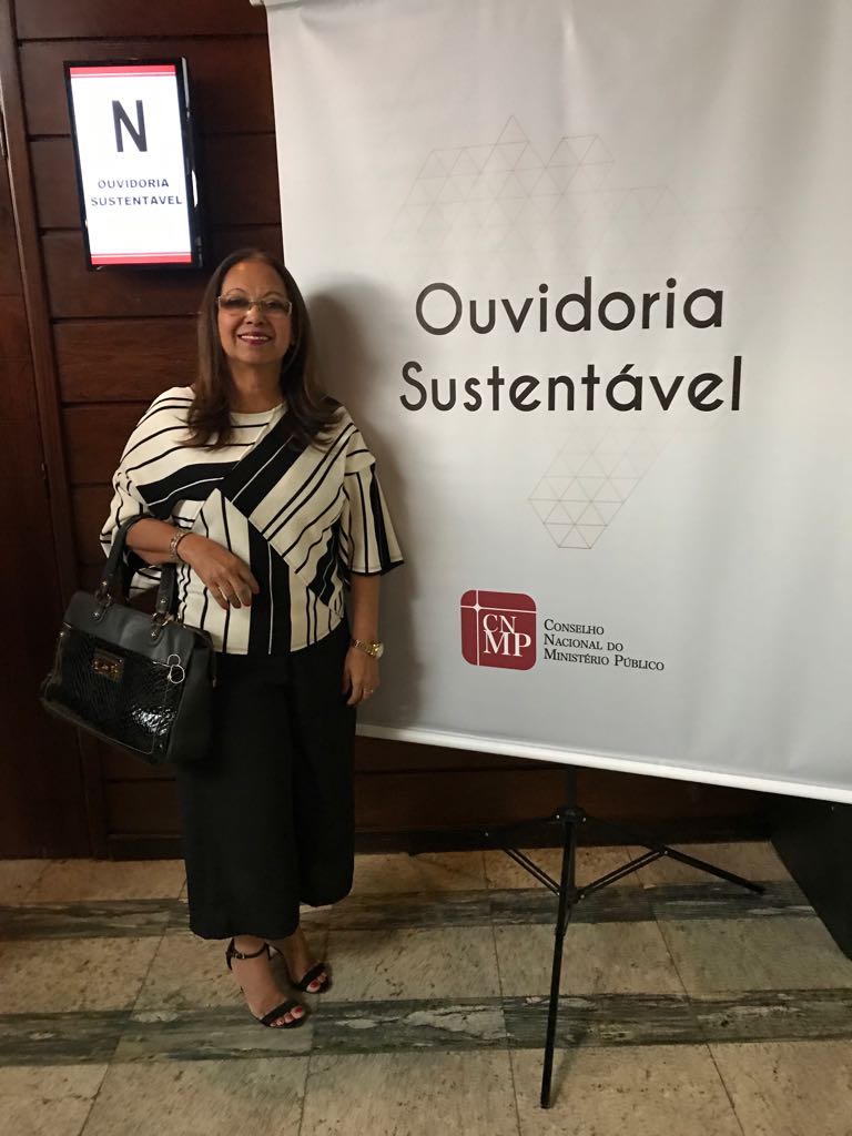 Procuradora Rosangela Mendes diante de um banner em que se lê 
