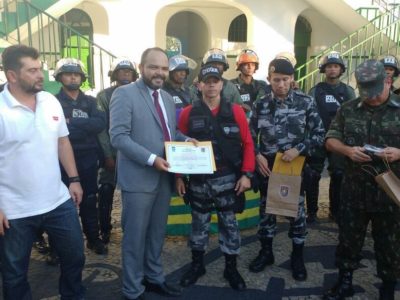 Promotor de Justiça recebe diplom de participação, ao lado de vários policiais fardados