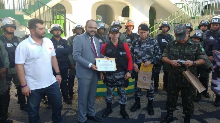 Promotor de Justiça recebe diplom de participação, ao lado de vários policiais fardados