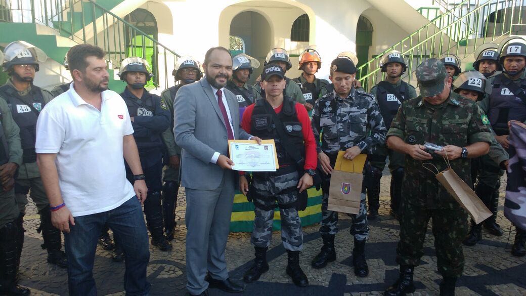 Promotor de Justiça recebe diplom de participação, ao lado de vários policiais fardados