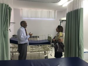 Promotora de Justiça conversa com representante da maternidade em sala onde há leitos de hospital.