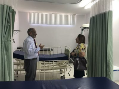 Promotora de Justiça conversa com representante da maternidade em sala onde há leitos de hospital.