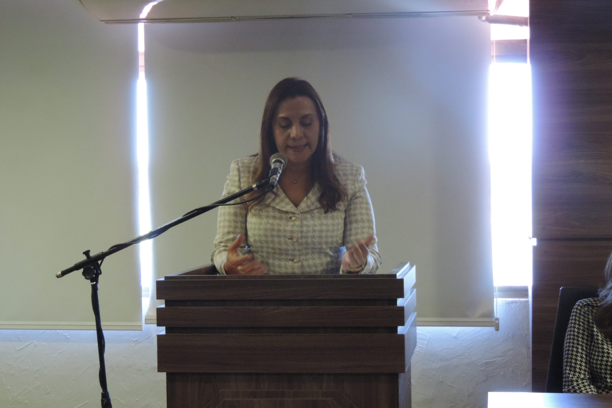 Mulher de pé falando com microfone nas mãos