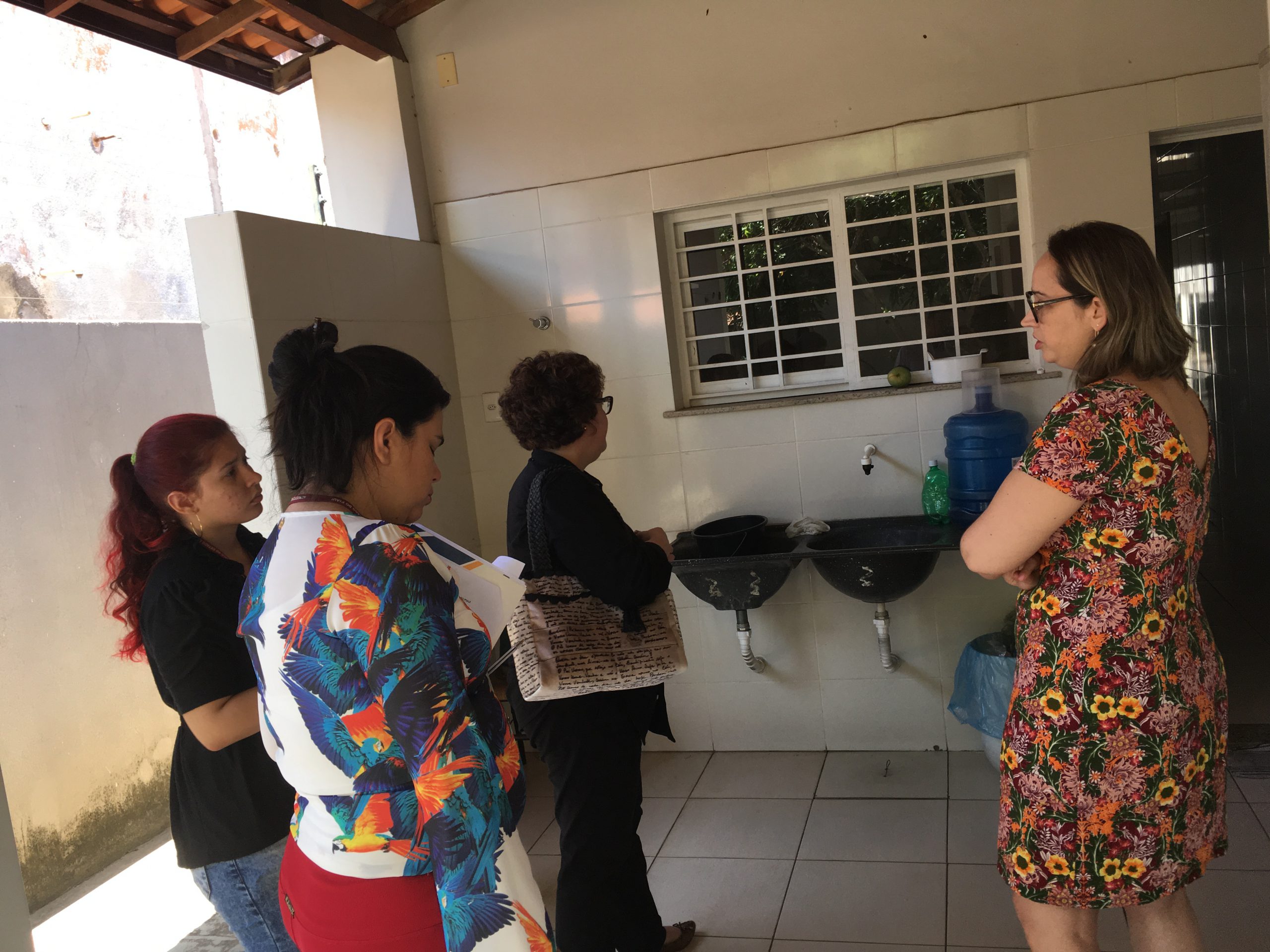 Pessoas de pé conversando entre si enquanto olham a parte externa de uma casa