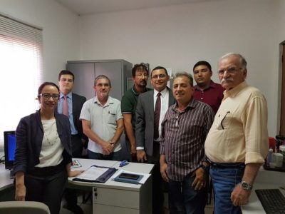 Pessoas de pé, dentro de uma sala de escritório, olhando para fotografia