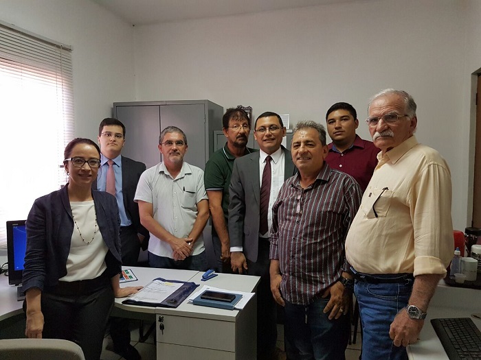 Pessoas de pé, dentro de uma sala de escritório, olhando para fotografia