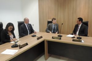 Pessoas sentadas em bancada. Dois homens se olham enquanto conversam