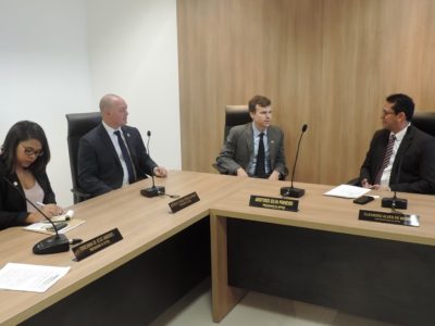 Pessoas sentadas em bancada. Dois homens se olham enquanto conversam