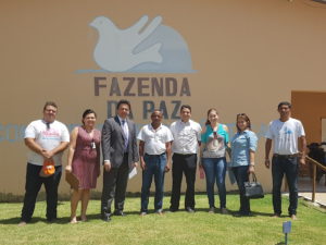 Equipe de inspeção posa em de pé em ambiente aberto. Atrás, estão pintados na parede os dizeres
