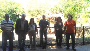 Equipe de inspeção posa em frente à célula em que está alojado um casal de leões.