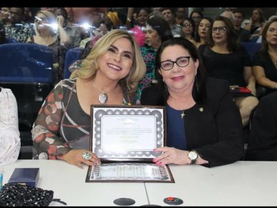 Duas mulheres sentadas em uma mesa. As duas segura uma placa