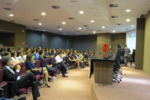 Pessoas sentadas em auditório assistindo palestra