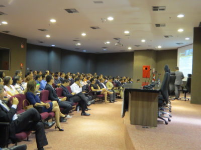 Pessoas sentadas em auditório assistindo palestra