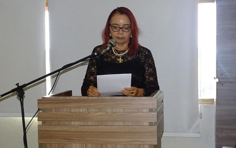 Pessoa de pé atrás de uma tribuna fazendo um pronunciamento. No momento a mesma pessoa segura alguns papéis nas mãos