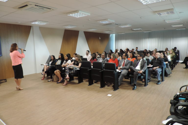 Pessoas sentadas olhando um mulher que está de pé