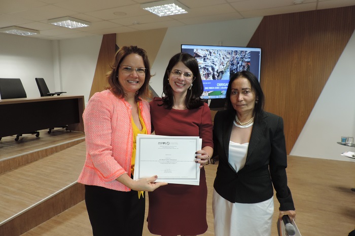 Três pessoas de pé sorrindo e segurando um certificado