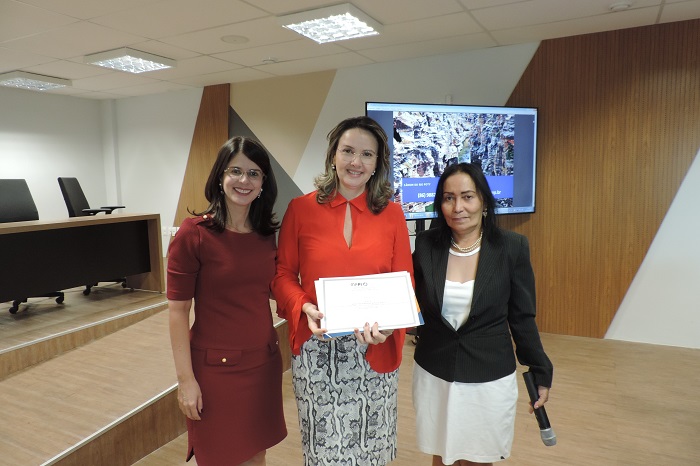 Três pessoas de pé segurando um certificado