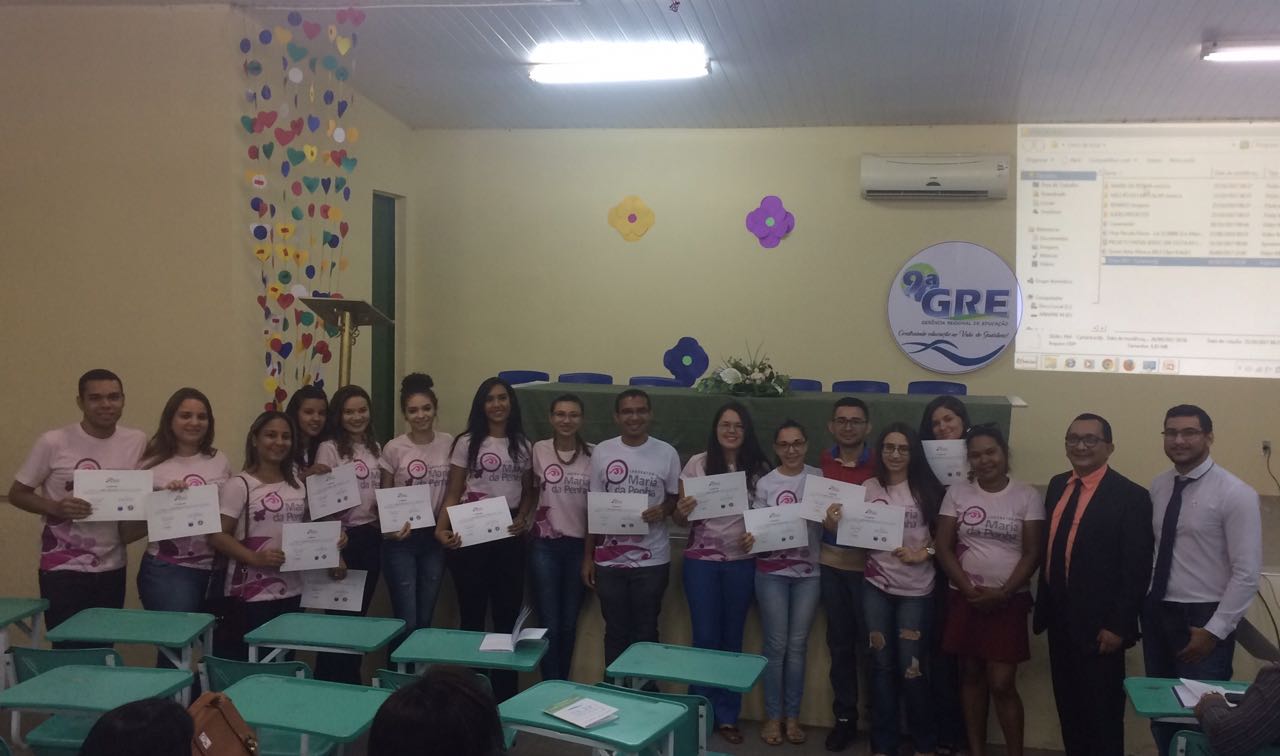 Pessoas de pé segurando certificados com as mãos e sorrindo para fotografia 
