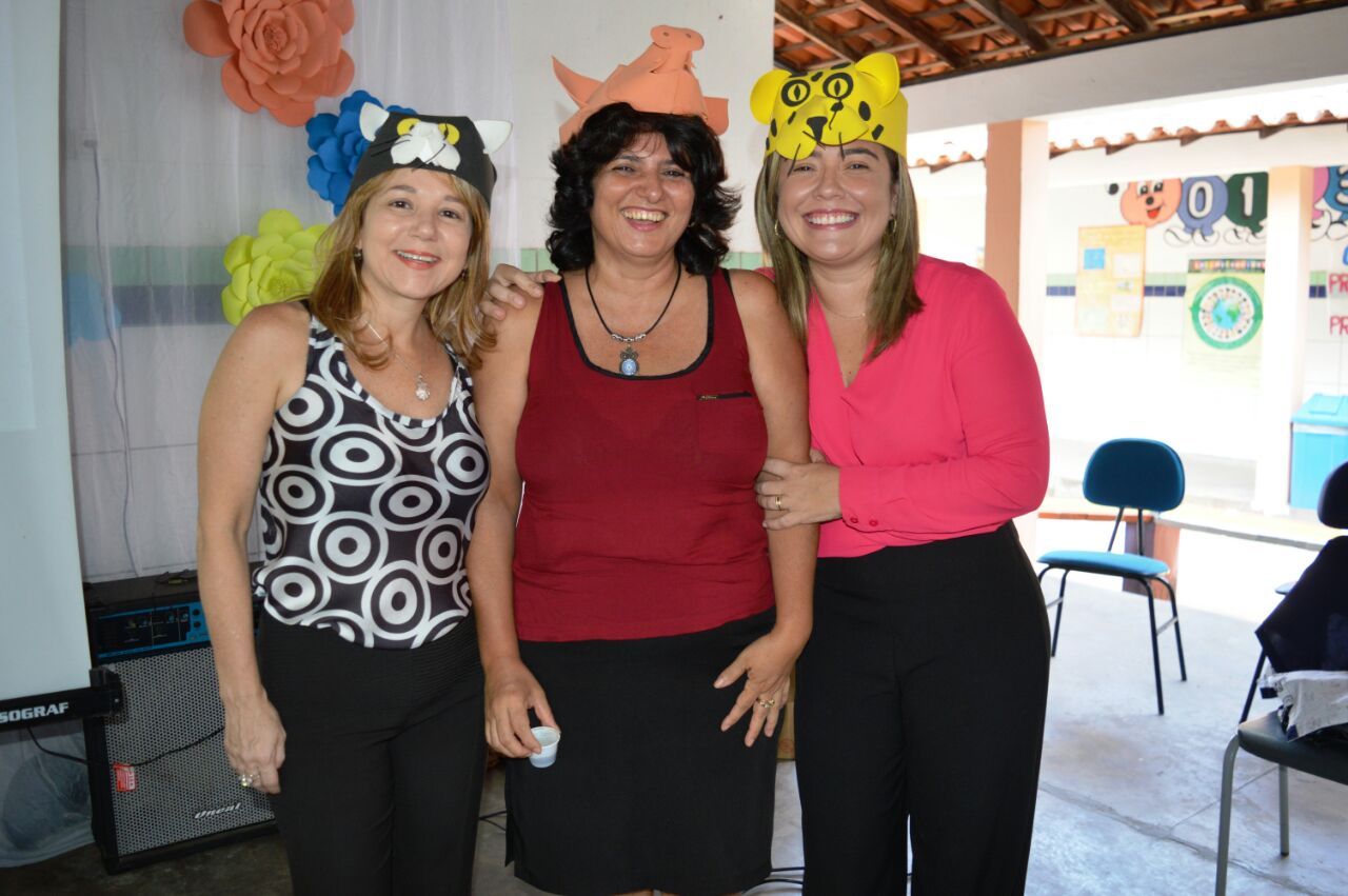 Três pessoas de pé com enfeites na cabeça e sorrindo
