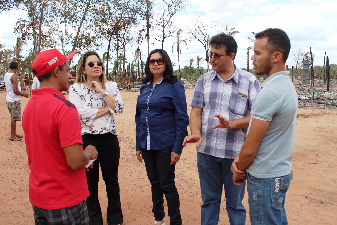 Pessoas de pé conversando entre si no cenário onde ocorreu o incêndio 