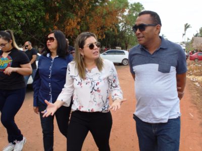 Pessoas caminhando enquanto conversam, ao centro uma mulher fala enquanto gesticula com as mãos