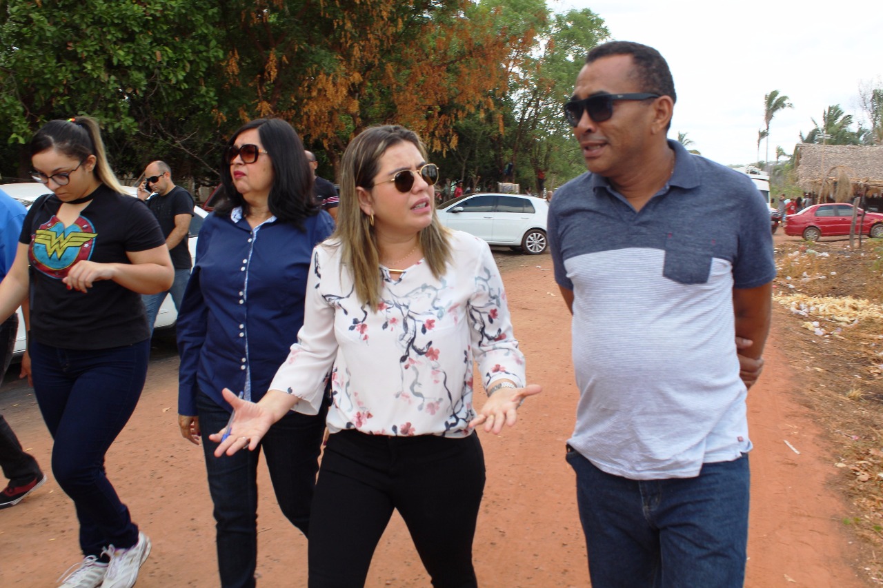 Pessoas caminhando enquanto conversam, ao centro uma mulher fala enquanto gesticula com as mãos