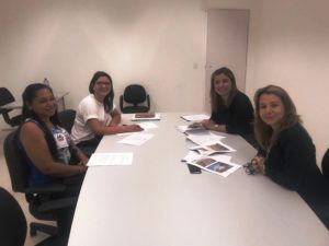 Quatro pessoas sentadas em uma mesa olhando para a pessoa que faz a fotografia