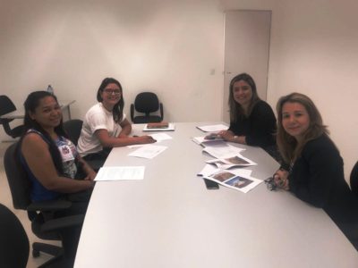 Quatro pessoas sentadas em uma mesa olhando para a pessoa que faz a fotografia