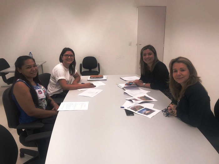 Quatro pessoas sentadas em uma mesa olhando para a pessoa que faz a fotografia