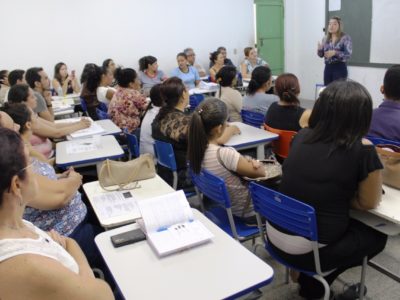 Professores reunidos em uma sala de aula, ouvindo exposição da promotora Flávia Gomes