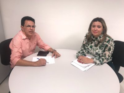 Promotora Flávia Gomes e secretário Zé Santana sentados junto a uma mesa redonda