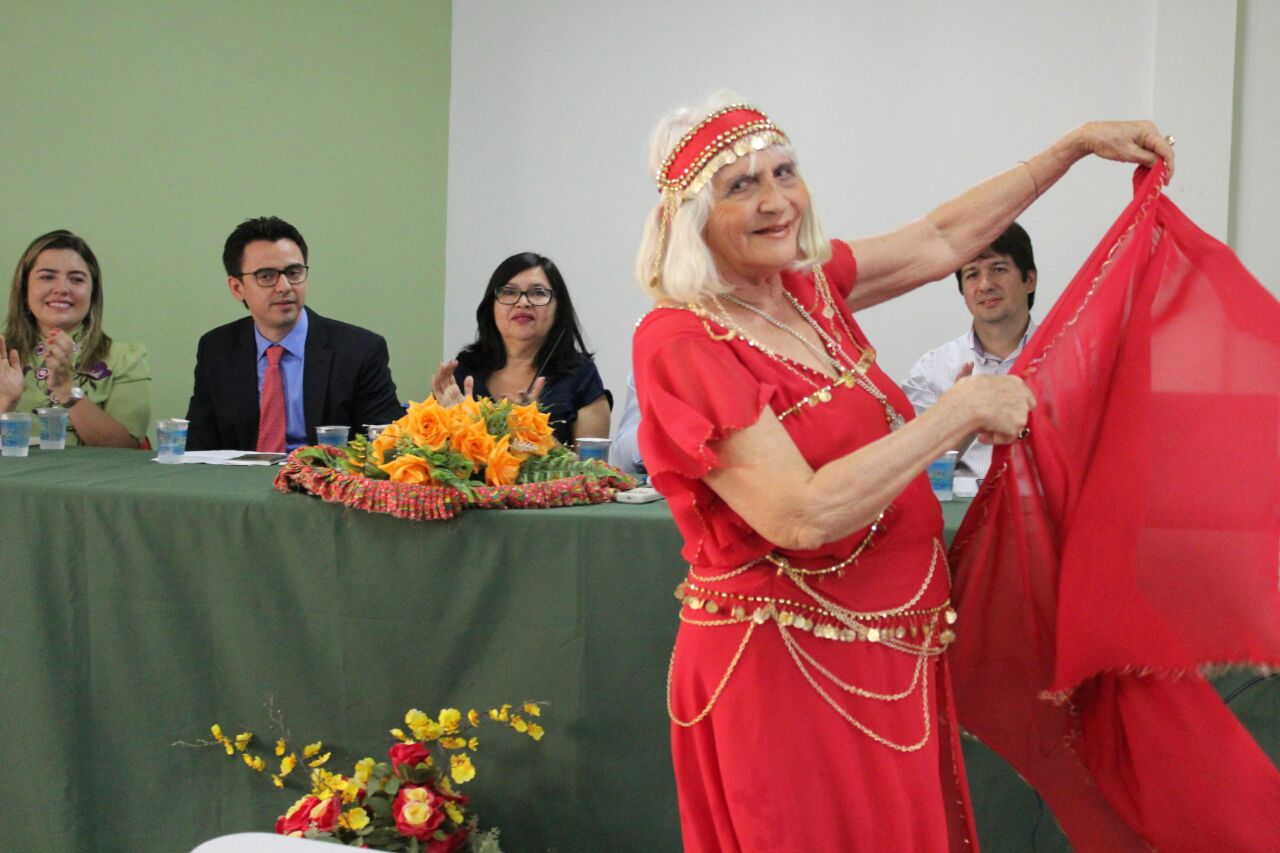 Senhora idosa dançando diante de mesa de honra do evento
