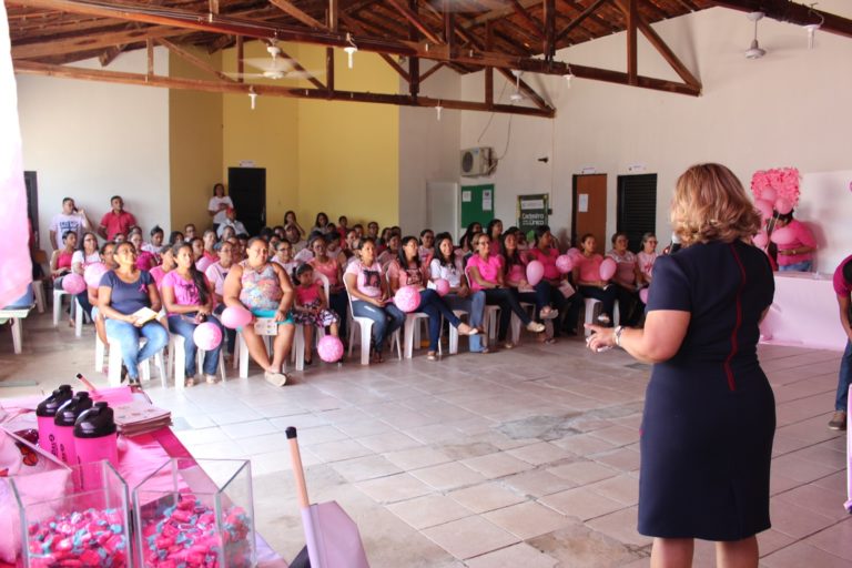 Promotora de Justiça fala para pessoas em auditório todo decorado com balões cor de rosa