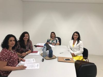Pessoas reunidas em torno de um mesa de reuniões, assinando documentos