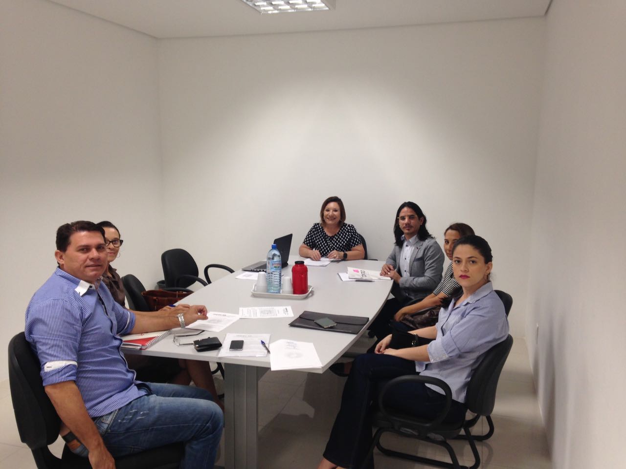 Pessoas reunidas em torno de uma mesa, sob a coordenação da Promotora de Justiça Maria das Graças do Monte Teixeira.
