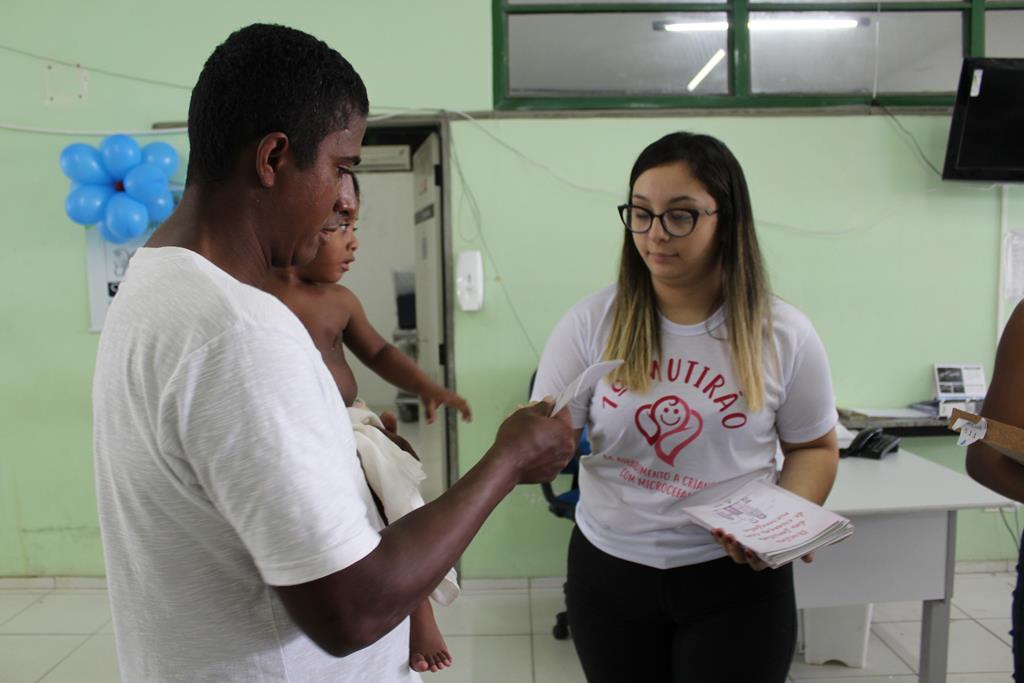 Duas pessoas de pé segurando uma cartilha 