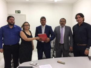 Pessoas de pé segurando um documento com as mãos