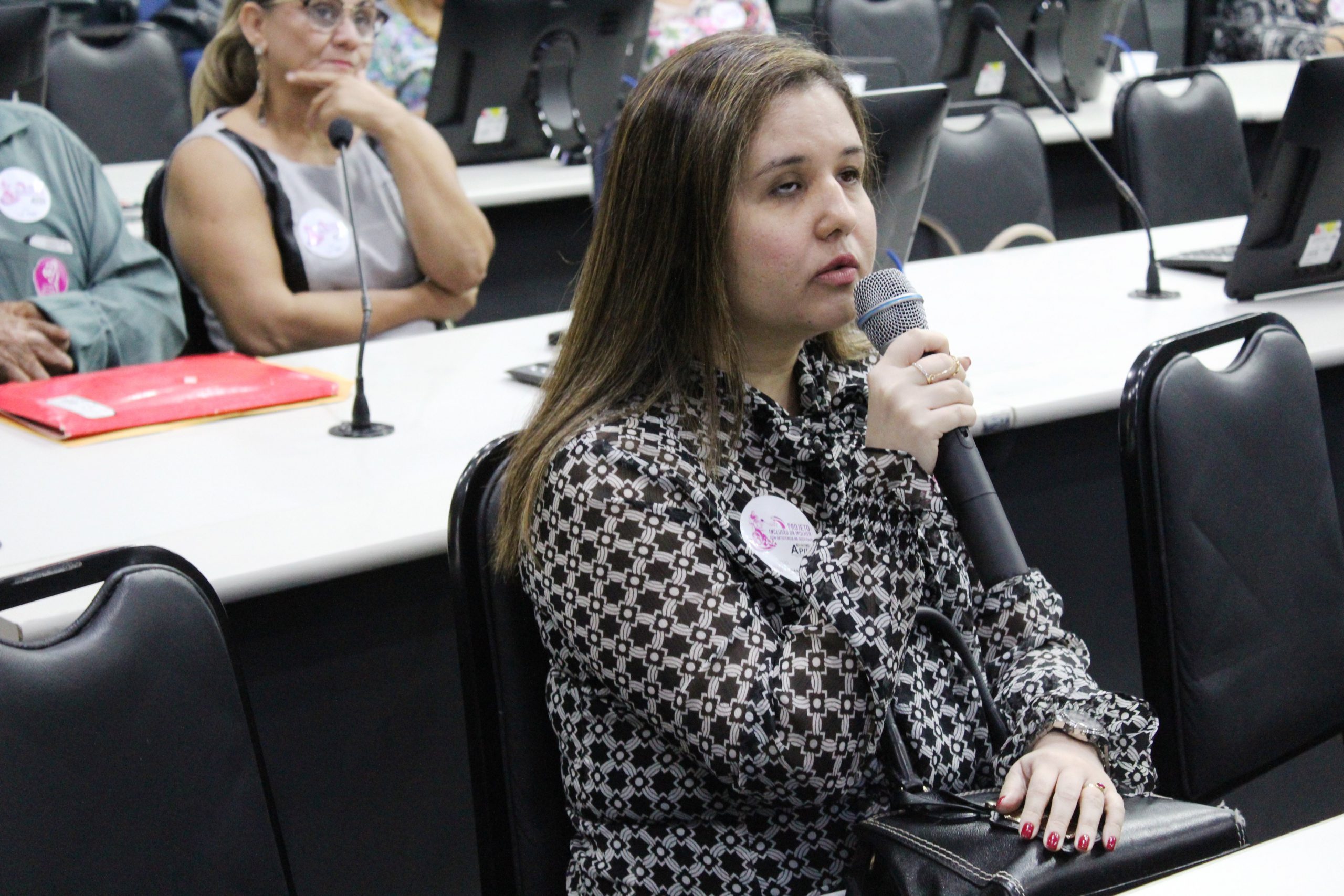 Mulher que é deficiente visual sentada falando com o microfone nas mãos