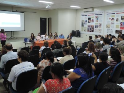 Pessoas sentadas em auditório assistindo palestra