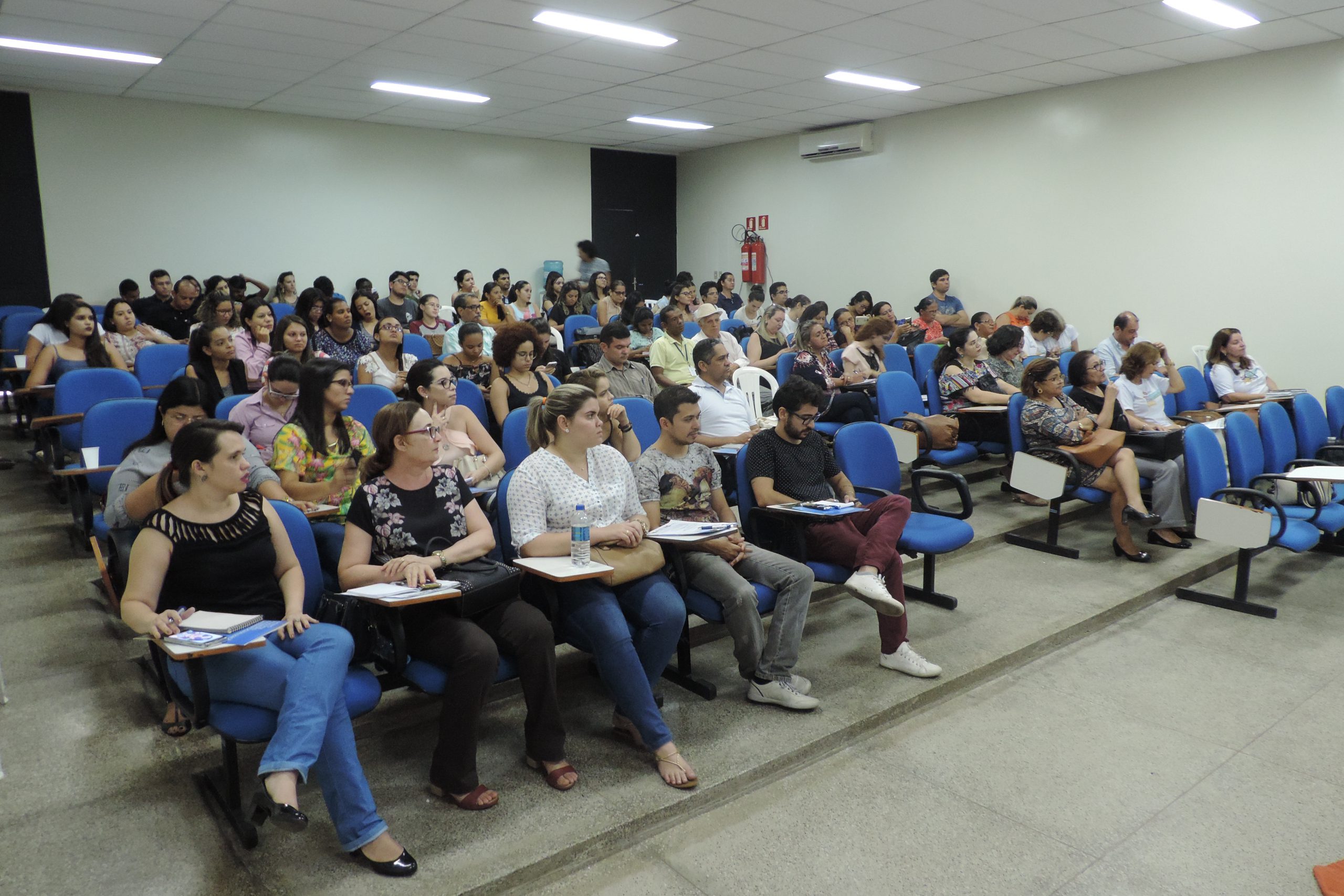 Pessoas sentadas em auditório assistindo palestra