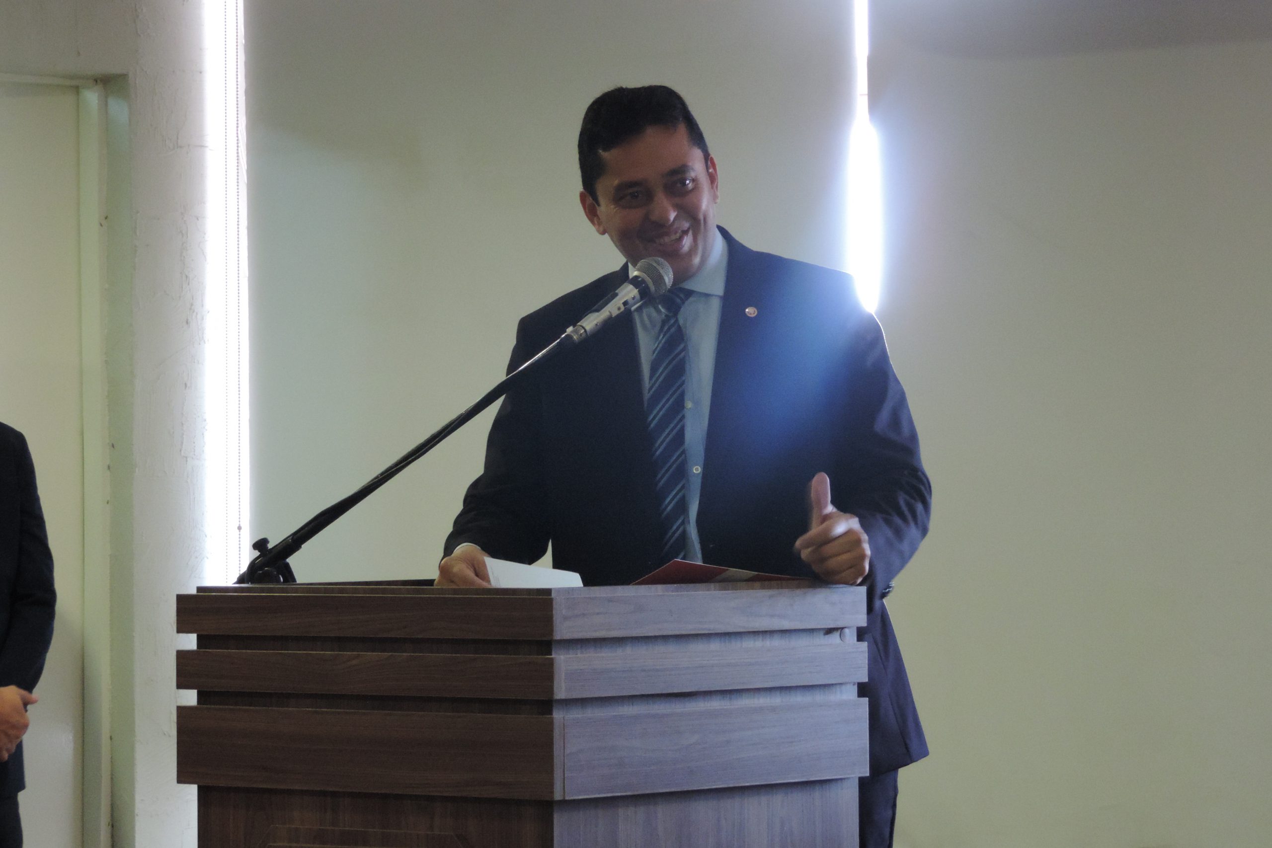 Homem de pé falando de uma tribuna 