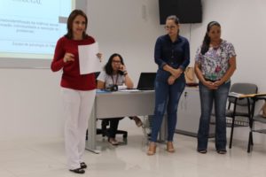 Mulheres de pé conversando com pessoas que estão a sua frente e sentados