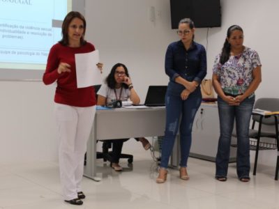 Mulheres de pé conversando com pessoas que estão a sua frente e sentados