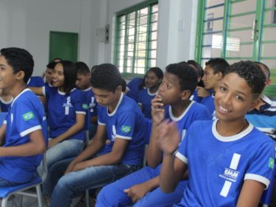Adolescentes e jovens sentados numa sala de aula assistindo uma palestra