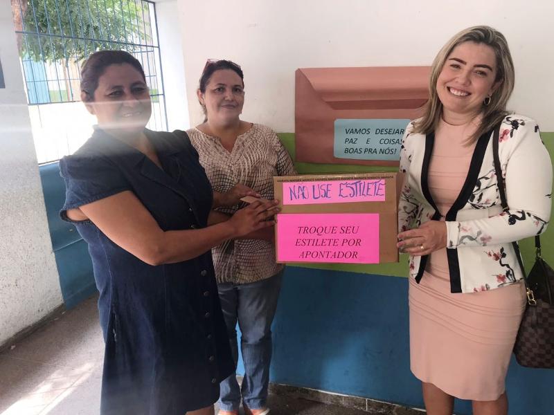 Três pessoas de pé segurando uma caixa com mensagem sobre o uso de apontador 