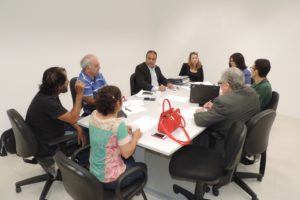 Pessoas sentadas em volta de uma mesa conversando umas com as outras