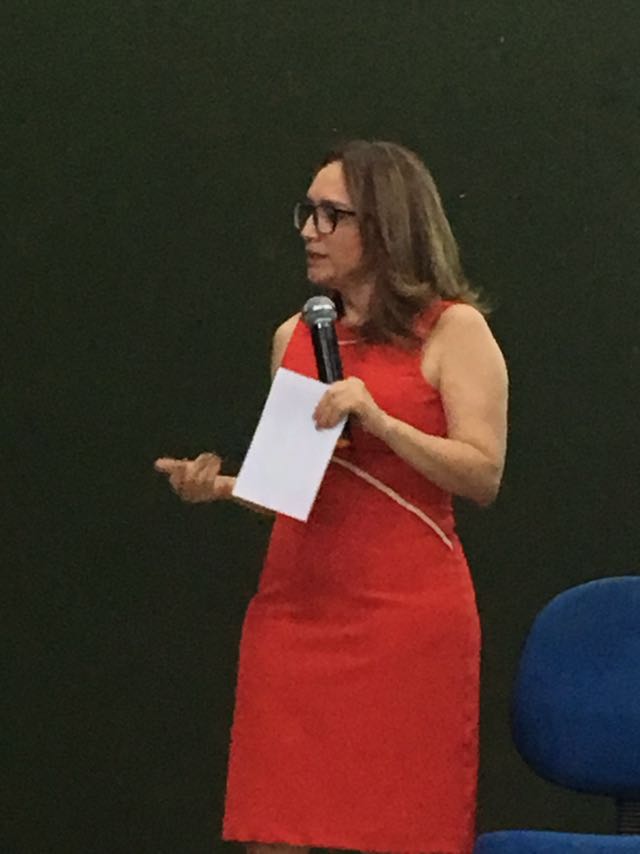 Mulher de pé falando com microfone nas mãos 